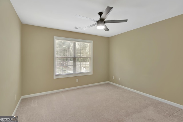 spare room with light carpet, a ceiling fan, and baseboards