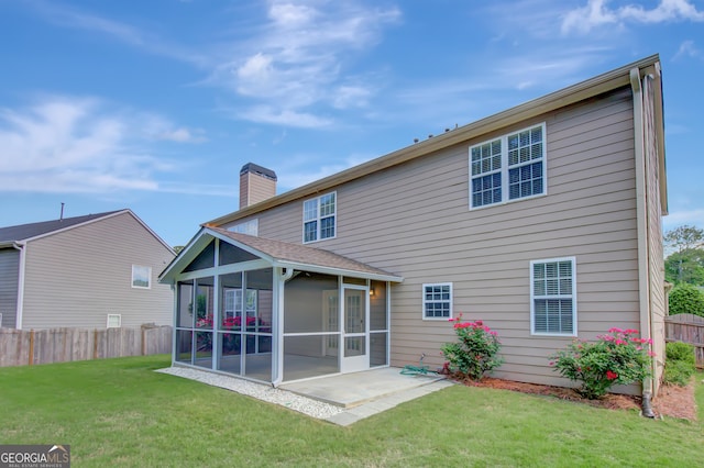 back of property with a sunroom, a chimney, and a patio area