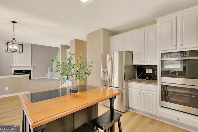 kitchen featuring appliances with stainless steel finishes, light wood-type flooring, tasteful backsplash, and white cabinets