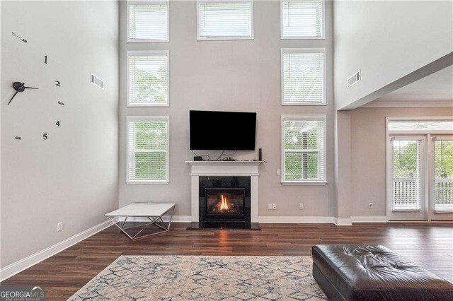6375 Haystack Ct, Cumming, GA 30040 - living room featuring a towering ceiling, wood finished floors, a glass covered fireplace, and visible vents