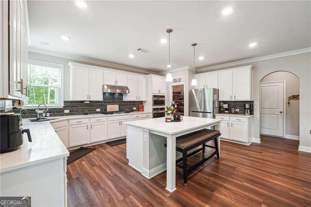 6375 Haystack Ct, Cumming, GA 30040 - kitchen with stainless steel appliances, a sink, under cabinet range hood, ornamental molding, and decorative backsplash