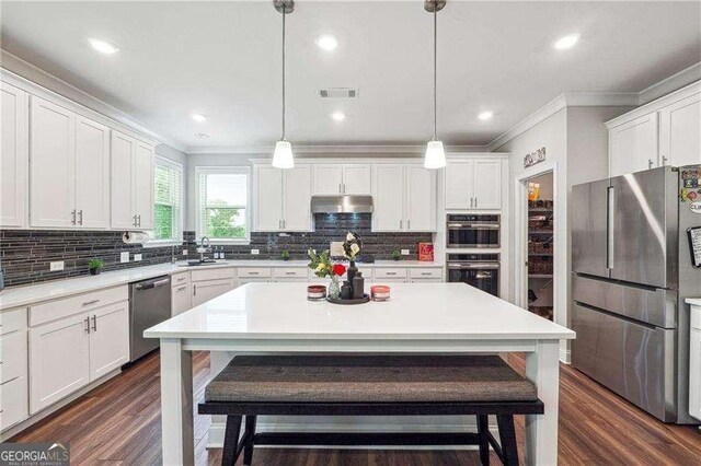 6375 Haystack Ct, Cumming, GA 30040 - kitchen with appliances with stainless steel finishes, crown molding, under cabinet range hood, a kitchen breakfast bar, and a sink