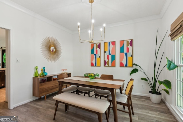 dining area with crown molding, a chandelier, and wood finished floors