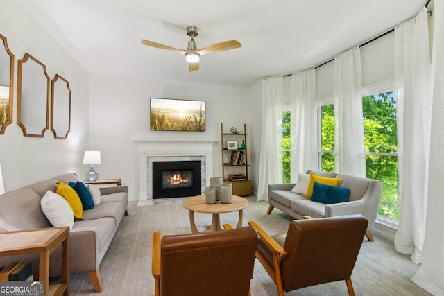 living area with a healthy amount of sunlight, a high end fireplace, and ceiling fan