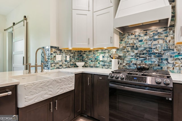 kitchen with light stone countertops, a sink, white cabinetry, wall chimney range hood, and stainless steel appliances