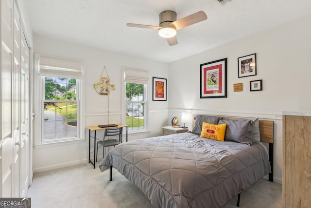 bedroom with baseboards, multiple windows, light carpet, and a ceiling fan