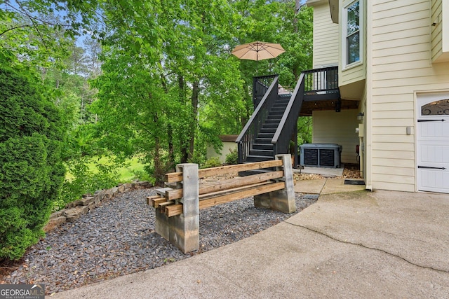 view of patio / terrace featuring driveway, a deck, a garage, and stairs