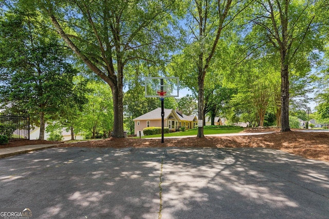view of basketball court with basketball hoop and fence