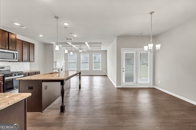 kitchen featuring appliances with stainless steel finishes, a sink, open floor plan, recessed lighting, and dark wood finished floors
