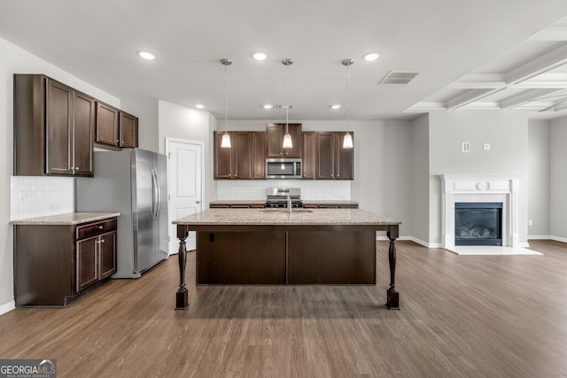 kitchen featuring stainless steel appliances, a breakfast bar, dark brown cabinetry, tasteful backsplash, and recessed lighting