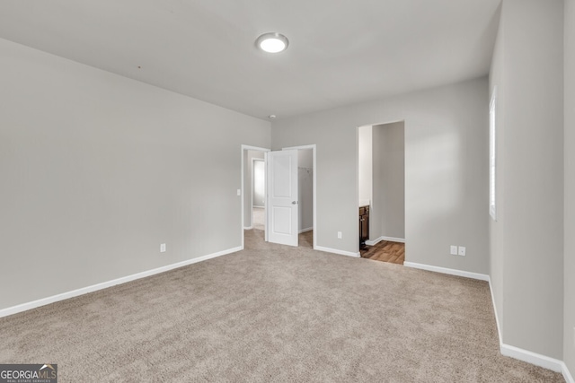 unfurnished bedroom featuring carpet floors, a spacious closet, baseboards, and a closet