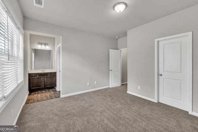 unfurnished bedroom with carpet floors, baseboards, and connected bathroom