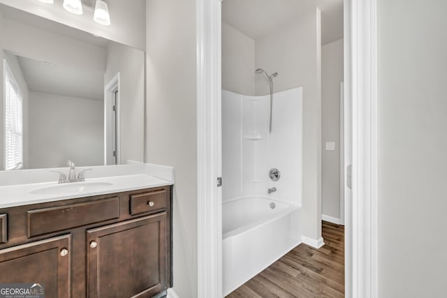 full bath with washtub / shower combination, vanity, wood finished floors, and baseboards