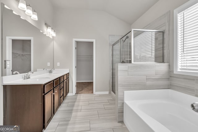 bathroom with lofted ceiling, a shower stall, a bath, a spacious closet, and double vanity
