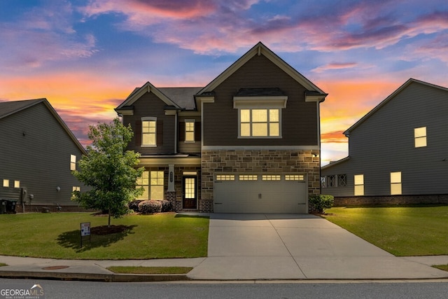 view of front of property with an attached garage, a yard, driveway, and stone siding