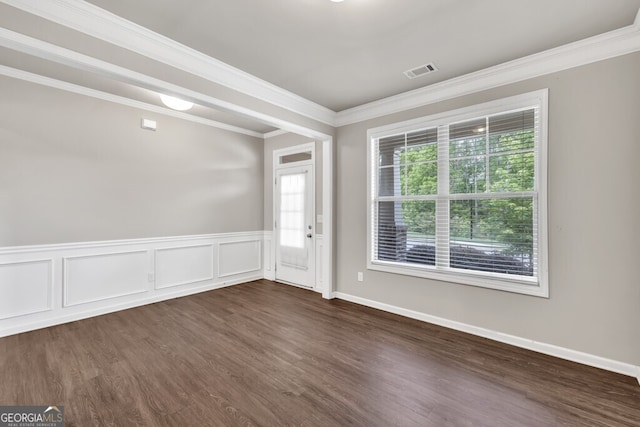 empty room featuring ornamental molding, dark wood-style flooring, and a wainscoted wall