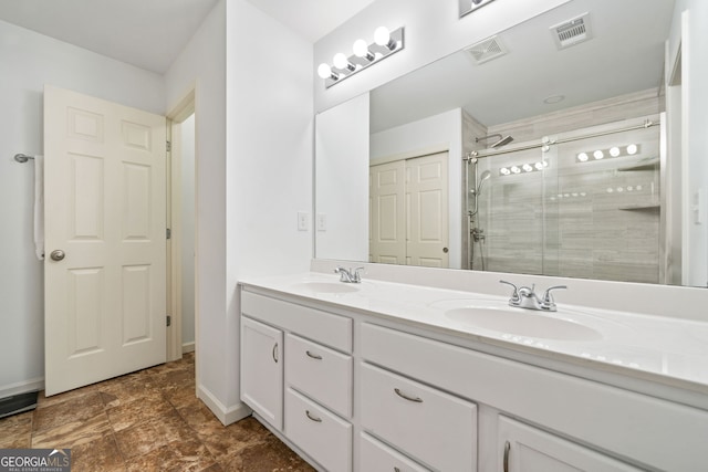 full bath featuring a stall shower, double vanity, and baseboards