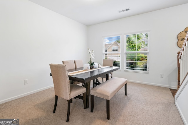 carpeted dining space with baseboards and stairway
