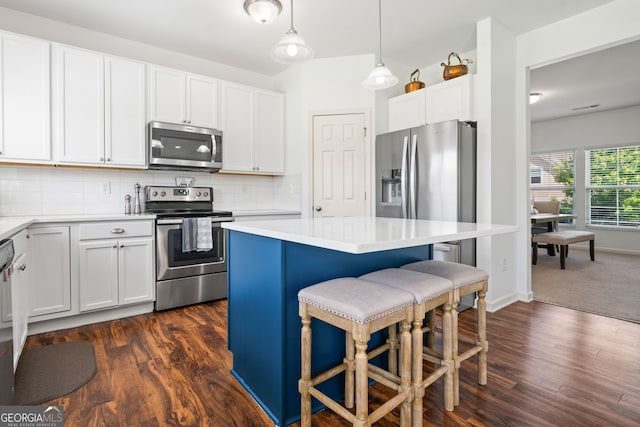 kitchen featuring stainless steel appliances, a breakfast bar area, light countertops, dark wood-type flooring, and a center island