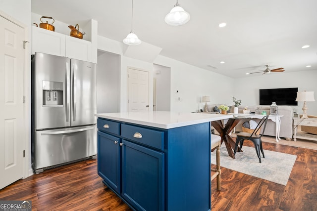 kitchen with stainless steel refrigerator with ice dispenser, blue cabinetry, ceiling fan, dark wood finished floors, and a center island