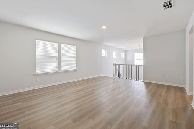 unfurnished room featuring baseboards, light wood-type flooring, visible vents, and recessed lighting