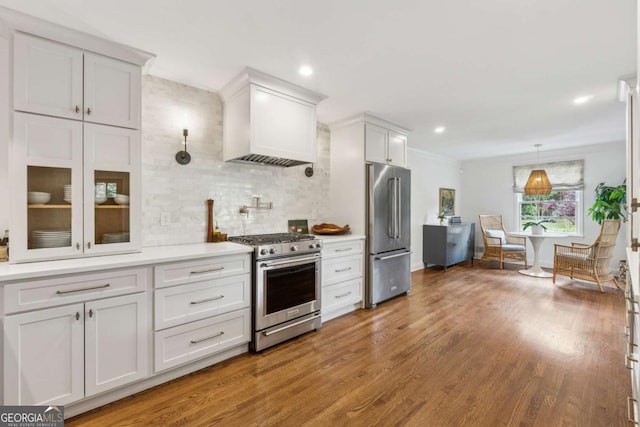 kitchen with appliances with stainless steel finishes, tasteful backsplash, custom range hood, light countertops, and wood finished floors