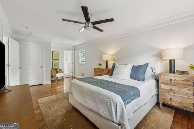bedroom with attic access, crown molding, wood finished floors, baseboards, and ceiling fan
