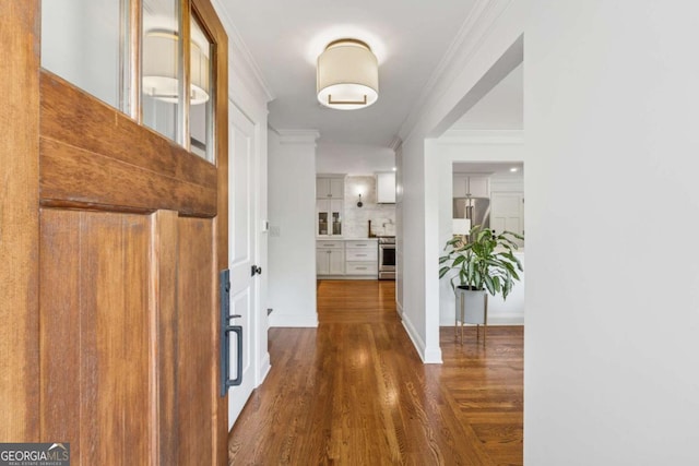 corridor featuring dark wood finished floors, ornamental molding, and baseboards