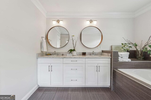 full bath with double vanity, ornamental molding, baseboards, and tiled tub