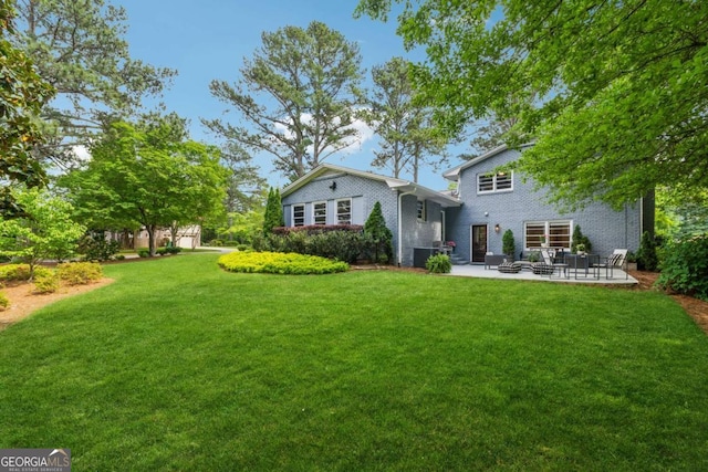 back of house with a patio area, a lawn, and brick siding