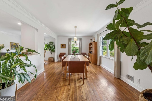 dining room with wood finished floors, baseboards, and ornamental molding