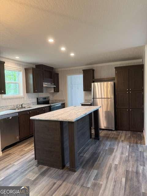 236 Dewaters Rd, Commerce, GA 30529 - kitchen with stainless steel appliances, light countertops, dark brown cabinets, ventilation hood, and wood finished floors