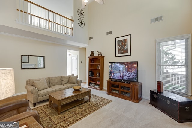living area featuring a high ceiling, baseboards, and visible vents