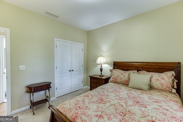bedroom with baseboards, a closet, visible vents, and light colored carpet