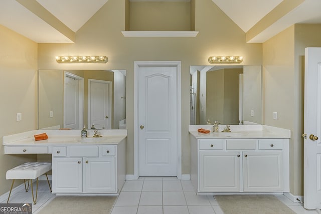 bathroom featuring baseboards, tile patterned flooring, two vanities, and a sink