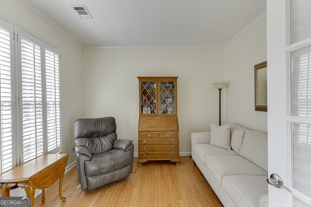 living area with baseboards, light wood-style flooring, and crown molding