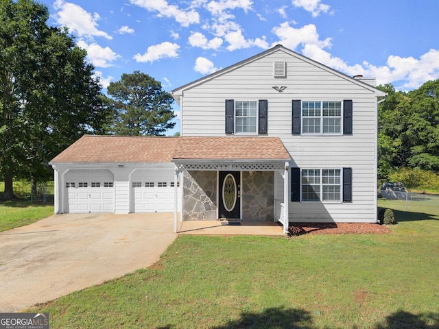 traditional-style home featuring a front yard, roof with shingles, driveway, and a garage