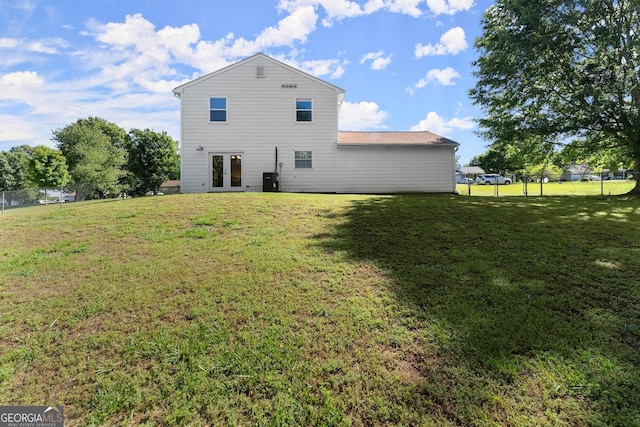 rear view of property with a yard, french doors, and fence