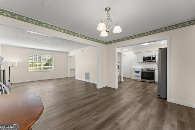 unfurnished living room featuring baseboards, a notable chandelier, and dark wood-type flooring
