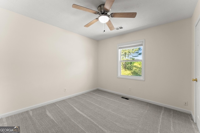 carpeted spare room with ceiling fan, baseboards, and visible vents