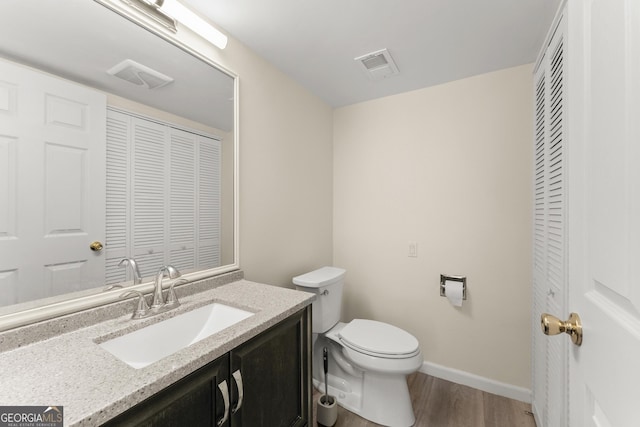 bathroom featuring toilet, wood finished floors, vanity, visible vents, and baseboards