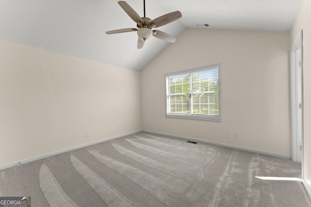 spare room with a ceiling fan, carpet floors, visible vents, baseboards, and vaulted ceiling