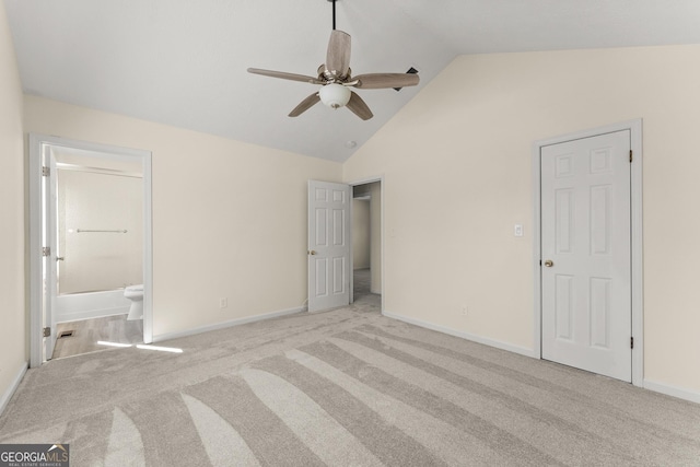 unfurnished bedroom with light colored carpet, connected bathroom, baseboards, and high vaulted ceiling