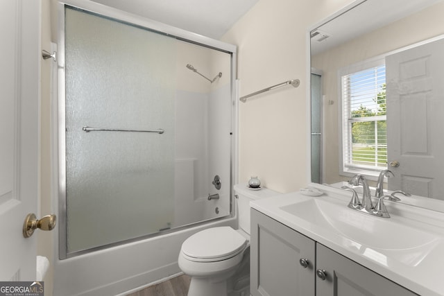 bathroom with toilet, wood finished floors, combined bath / shower with glass door, visible vents, and vanity