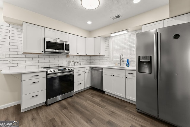 kitchen featuring a sink, dark wood-type flooring, visible vents, light countertops, and appliances with stainless steel finishes