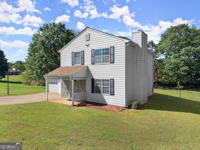 traditional-style home with a chimney, driveway, a front yard, and fence