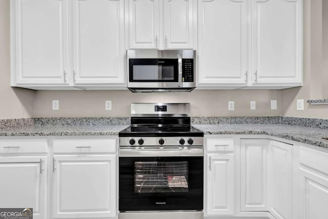 kitchen featuring stainless steel appliances, light stone counters, and white cabinets