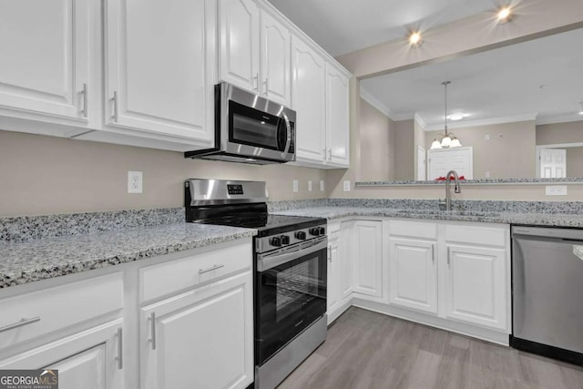 kitchen with a sink, stainless steel appliances, light wood-type flooring, white cabinetry, and a notable chandelier