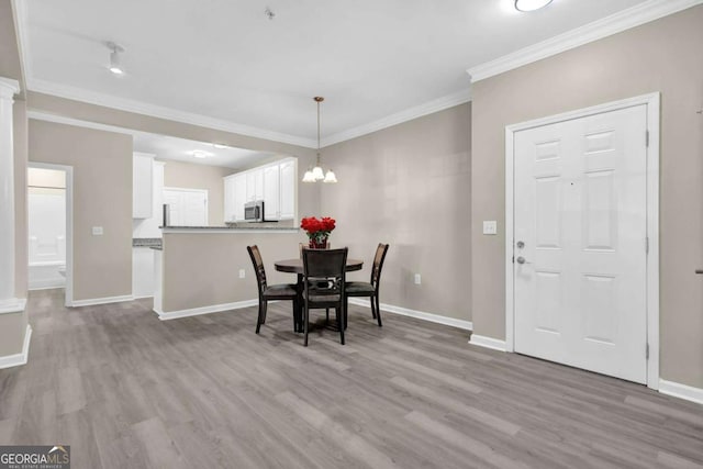 dining area with an inviting chandelier, ornamental molding, baseboards, and light wood-style floors