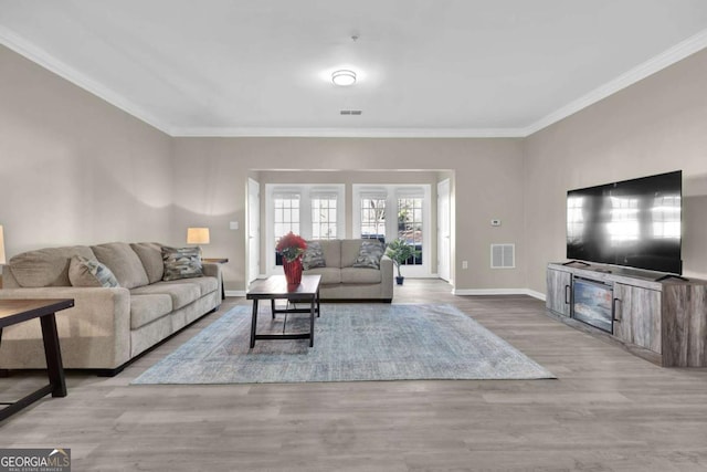 living room featuring baseboards, visible vents, crown molding, and wood finished floors